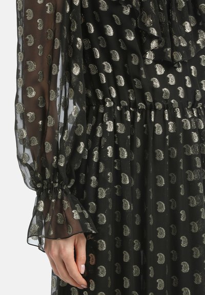 Zwarte doorschijnende jurk met een ruches halslijn, elastische manchetten en een metallic paisley patroon door de stof. Gelaagd en textuurontwerp.