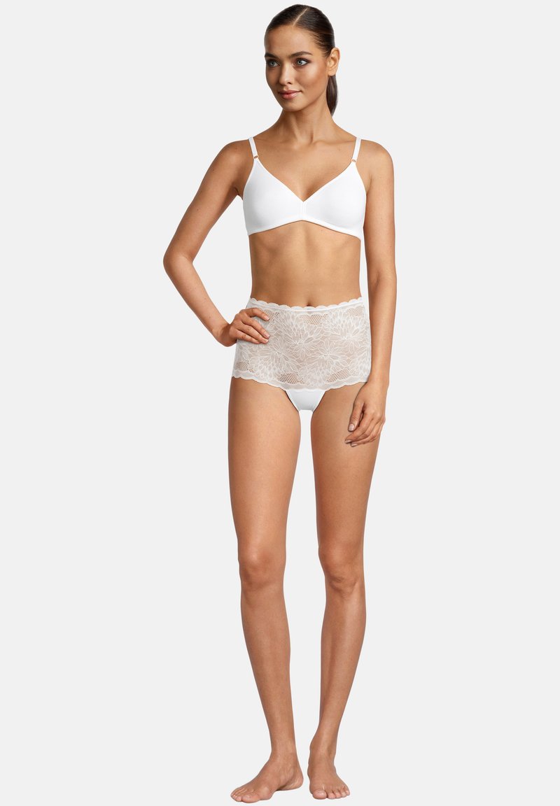 Weißes Bralette mit dünnen Trägern, kombiniert mit weißen hochgeschnittenen Panties, die mit floralem Spitzenbesatz versehen sind. Glatter Stoff mit gewellten Kanten.