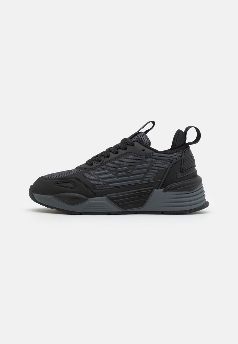 Black athletic sneakers featuring a mesh upper, textured panels, laces, and a logo detail. Thick rubber sole with a pronounced heel.