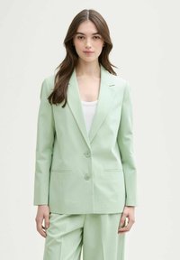 Mintgrüner Blazer aus glattem Material mit taillierter Passform, Reverskragen, zwei Knöpfen und Seitentaschen. Kombiniert mit passenden Hosen.