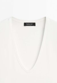 White V-neck top with visible Massimo Dutti brand label sewn inside the neckline.
