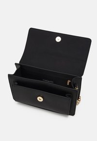 Czarna skórzana torba z klapą, złotymi elementami i łańcuszkiem. Wewnątrz znajduje się kieszeń na zamek oraz kilka przegrodek.