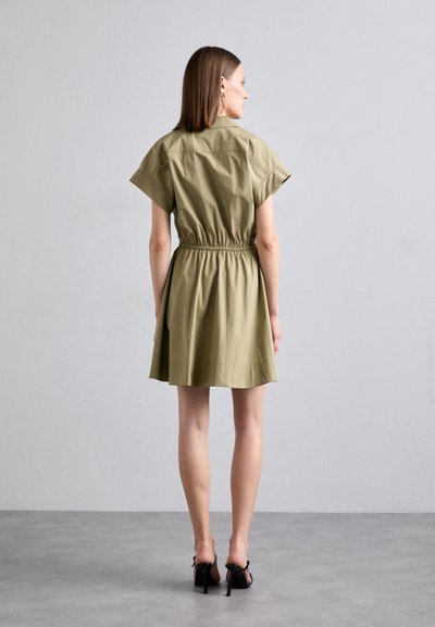 Olivenfarbes Baumwollkleid mit tailliertem Schnitt, kurzen Ärmeln und einem ausgestellten Rock. Glatte Textur, knielanges Design und minimale Details.