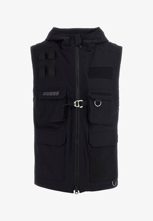 Zwarte vest met capuchon, ritssluiting, meerdere voorzakken en branding. Kenmerkt zich door textiel met structuur en verstelbare banden met een metalen ring.