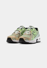 Mesh sneakers met een groen, beige en zwart kleurenschema, met contrasterende accenten, dikke zolen en een ronde teenontwerp.