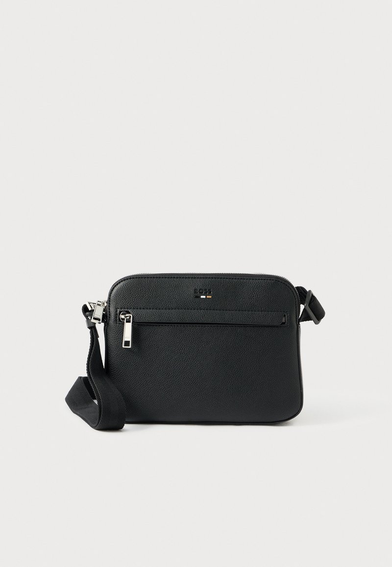 Černá kožená crossbody taška s texturovaným povrchem, vybavená přední kapsou na zip a nastavitelným popruhem. Součástí jsou kovový zip a kovové doplňky.