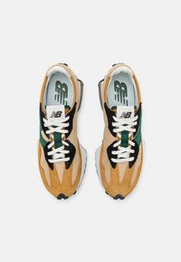 Tennarit, joissa on vaaleanruskea ja musta samettipinta, vihreät yksityiskohdat, valkoiset nauhat ja kuvioitu sisäpohja. Varustettu teksturoidulla pohjalla pidon parantamiseksi.