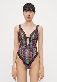 Maillot de bain à motifs arc-en-ciel avec des écailles brillantes, décolleté en V profond et bretelles noires. Présente des jambes hautes et une conception à couverture minimale.