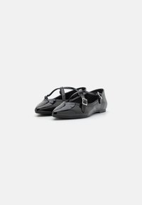 Bailarinas de charol negro con punta afilada, tiras cruzadas y acentos de hebilla metálica. Textura suave y diseño de perfil bajo.