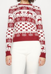 Rood en wit gebreide trui met rendieren, harten en sneeuwvlokpatronen, ronde hals, slim fit, en lange mouwen met geribbelde manchetten.