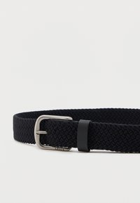 Μαύρη υφαντή ζώνη με ασημένια μεταλλική αγκράφα και μαύρη δερμάτινη θηλιά σε λευκό απλό φόντο.