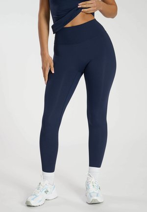 Leggings azul marino con una cintura alta y una tela suave y elástica; presentan costuras de contorno que recorren las piernas.