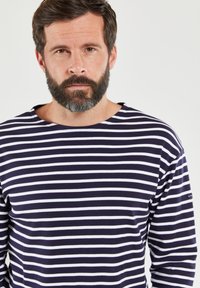 Marinblå og hvidstribet langærmet skjorte med rund halsudskæring. Stoffet ser blødt og glat ud og har et lille logo på ærmet.