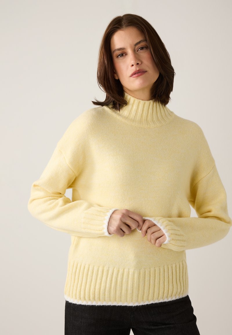 Yellow knit sweater with a high ribbed collar, ribbed cuffs, and a textured body. White accents at sleeves and hem. Cozy, relaxed fit.