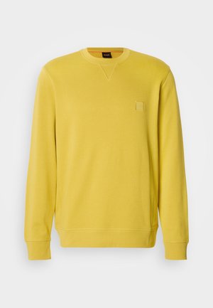 Kollane pika varrukaga ümara kaelusega pusapluus, tehtud pehmest kangast, millel on rinnal väike tikitud logoplaat.
