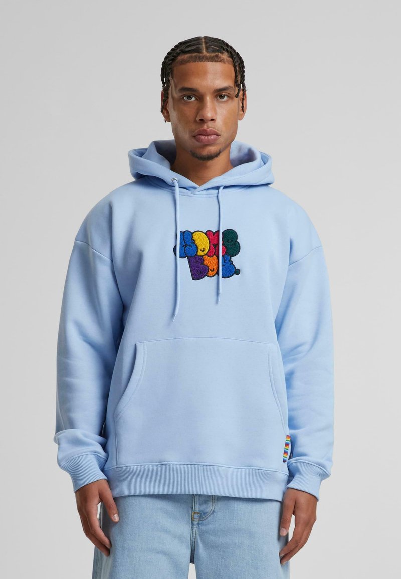 Hellblaues Kapuzenshirt mit einer Fronttasche, das ein gesticktes mehrfarbiges Design stilisierter Buchstaben aufweist. Rippenärmel und -saum.