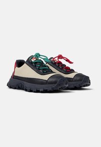 Zapatillas casuales con parte superior de lienzo color crema, detalles de cuero azul marino y cordones multicolores en rojo y verde, con una suela negra resistente.