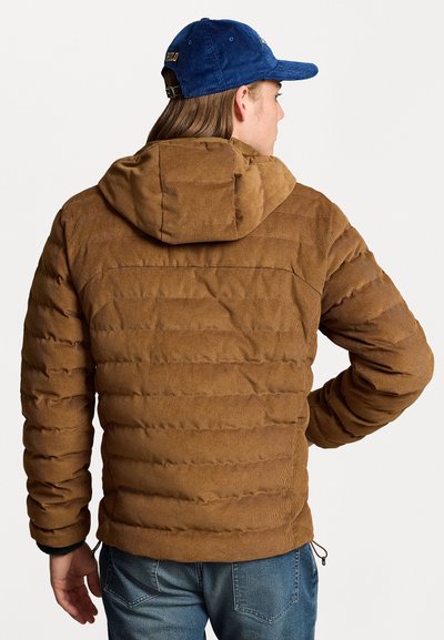 Brown puffer jacket with textured corduroy fabric and horizontal quilting. Features a hood and adjustable hem. Worn over blue jeans.