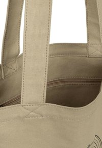 Sac fourre-tout en toile beige avec poignées cousues et poche intérieure zippée, montrant la texture détaillée du tissu et les coutures.