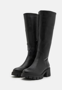 Black knee-high boots made of smooth leather with a chunky, ribbed sole and a side zipper detail. Sleek design with a rounded toe.