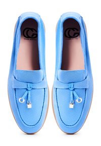Paire de mocassins en daim bleu avec semelles intérieures en cuir, glands décoratifs et semelles beige clair, vus de dessus.