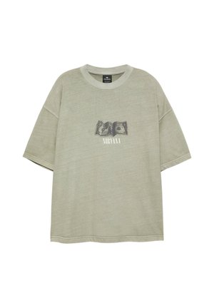 Hell olivgrünes oversized T-Shirt mit kurzen Ärmeln und einem verblassten schwarzen Motiv gefalteter Dollarnoten sowie dem Wort Nirvana darunter.