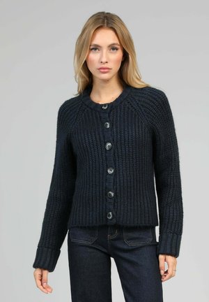 Cardigan en maille bleu marine avec un col rond, texture côtelée et six grands boutons noirs sur le devant. Silhouette ajustée, manches longues.