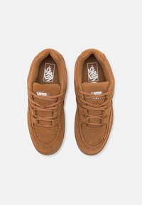 Braune Wildleder-Sneaker mit abgerundeter Zehenpartie, Schnürdesign und strukturierten Akzenten. Mit weißem Markenlogo auf der Zunge und an der Seite.