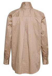 Chemise beige à manches longues vue de dos avec un col montant, un pli central et des poignets boutonnés sur fond blanc.