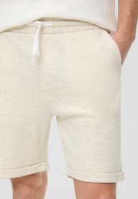 Cremfarbene Baumwollshorts mit texturierter Oberfläche, seitlichen Taschen und einem elastischen Bund mit Kordelzug. Umschlagenden am Saum.