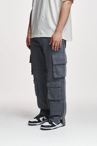 Pantaloni cargo gri cu mai multe buzunare cu clapetă, croi lejer și fermoare laterale. Purtați cu adidași negri și albi. Tricoul este de culoare gri deschis.