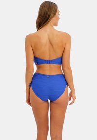 Blue bikini set featuring a strapless top and high-waisted bottom. Textured fabric with side ties on the bottoms and metallic accent detail.