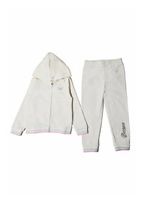 Tuta in pile bianco composto da una felpa con zip e maniche con strisce arcobaleno e pantaloni abbinati. I pantaloni hanno la scritta "Guess" ricamata sulla gamba.