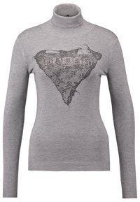 Pull gris à manches longues et col roulé avec un motif triangulaire texturé en dentelle et logo "GUESS" clouté sur la poitrine.