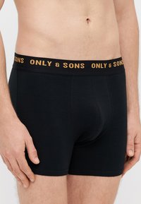 Černé boxerky z bavlny s elastickým pasem s nápisem "ONLY & SONS" zlatým písmem. Hladká textura, přiléhavý střih.