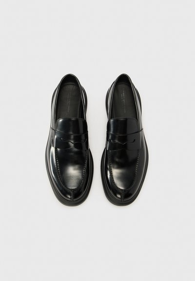 Loafers din piele neagră, cu un finisaj neted, având un vârf rotund, detalii cusute și un accent subtil sub formă de fundiță pe partea superioară.