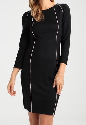 Robe noire ajustée à manches trois-quarts, avec des coutures contrastantes de couleur rose clair qui dessinent la silhouette. Texture lisse, longueur au-dessus du genou.