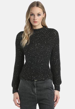 Pulover negru din tricot cu striații, cu sclipici metalic, guler înalt și talie ajustată, având mâneci lungi tip balon. Asortat cu blugi în nuanțe închise.