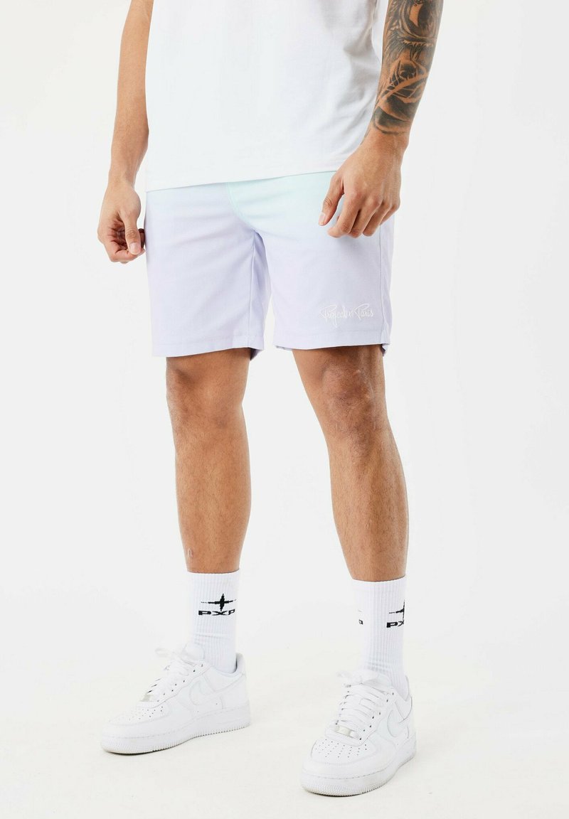 Shorts de bain violet clair avec une texture lisse et un logo blanc, associés à des baskets blanches et des chaussettes montantes avec un accent noir.