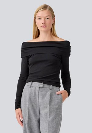 Black off-the-shoulder top with long sleeves, featuring gathered detail at the neckline. Paired with light gray houndstooth high-waisted trousers.