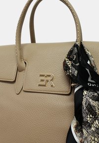 Borsa a mano in pelle beige con forma strutturata, caratterizzata da un logo dorato e una sciarpa nera con motivo legata al manico.
