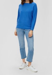 Blårandig stickad tröja med rund halsringning, långa ärmar och ribbade ärmar, i kombination med ljusblå beskurna jeans och vita sneakers.