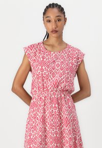 Floral-patterned dress in pink and white, featuring cap sleeves, a round neckline, and an elastic waistband for a relaxed fit.