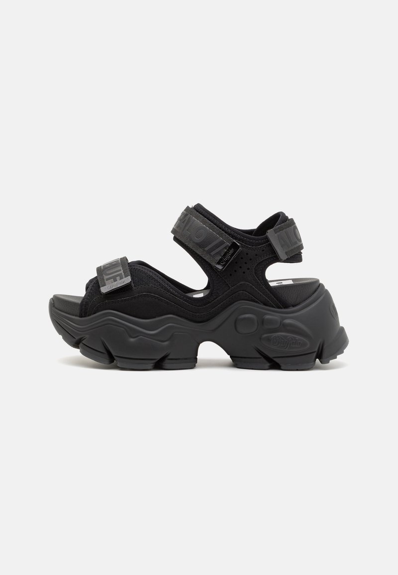 Sandales noires ouvertes à l'avant avec des semelles épaisses et texturées et des sangles ajustables. Fabriquées dans un matériau doux avec des accents perforés.