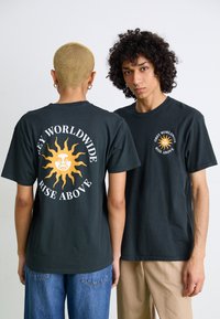 Svart bomulls t-skjorte med en gul solgrafikk og tekst på baksiden. Forsiden har en liten sollogo. Klassisk crew neck-design.