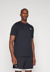 Black short-sleeve t-shirt made of cotton with a round neckline and a small logo on the chest, paired with black athletic shorts.