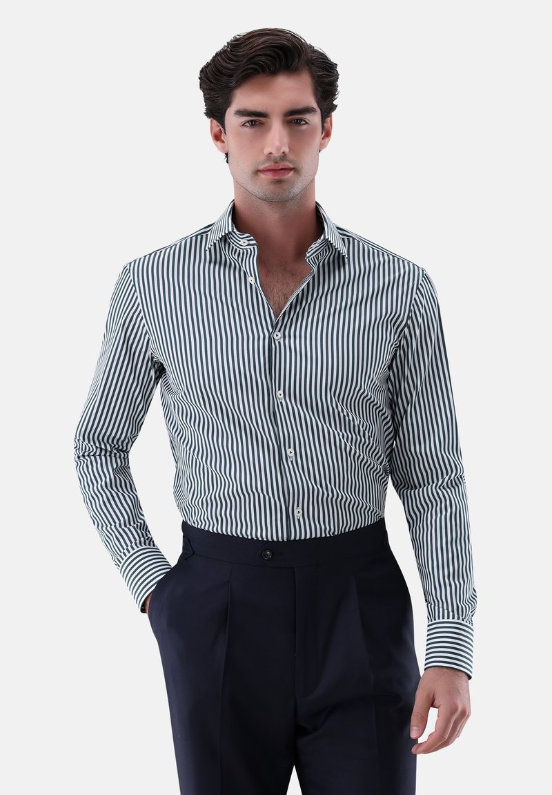 Herren Langarmhemd mit schmalen grünen und weißen Streifen, Button-Down-Kragen und strukturiertem Stoff. Kombiniert mit marineblauen Hosen.