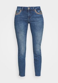 Smala jeans i medelblå denim. Har dekorativ söm på framfickor, en knappknäppning och siddragkedjor vid anklarna.