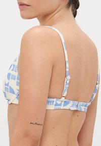 Fehér és kék mintás bikini felső állítható pántokkal, textúrált felülettel és hátsó kapoccsal.
