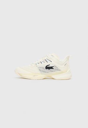 Lacoste athletic shoes in cream with black logo. Features mesh upper, textured sole, and lace-up design for secure fit. Lightweight construction.